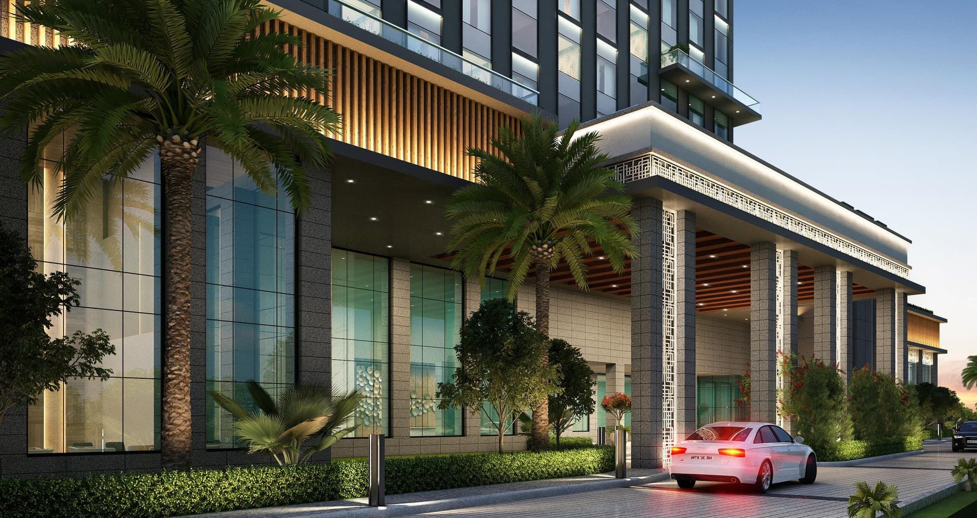 The porte-cochère entrance to Sandal Suites Shirdi at dusk, lit and framed by palms